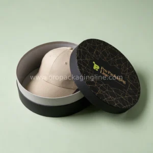 Black round rigid hat box with gold print and cap inside