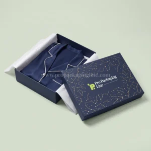 Midnight indigo two-piece sleepwear box with gold constellation lid and navy silk pajamas, Pro Packaging Line logo